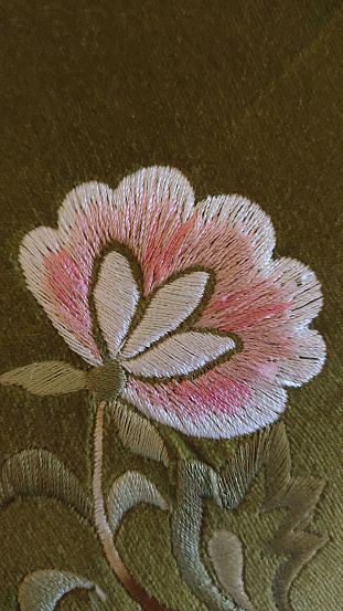 closeup of a pink and white flower embroidered on a green background