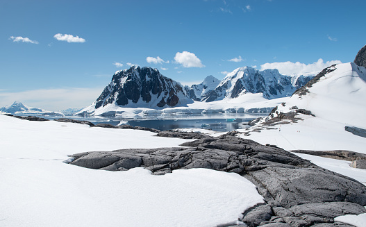 Travel and expedition image with snow, mountains and bay at port Charcot, Booth Island in Antarctica. Stunning peaceful winter landscape with blue sky in January.