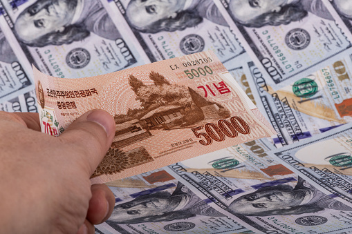 A Bill Of 5000 North Korean Won In A Mans Hand Against The Background a-bill-of-5000-north-korean-won-in-a-mans-hand-against-the-background