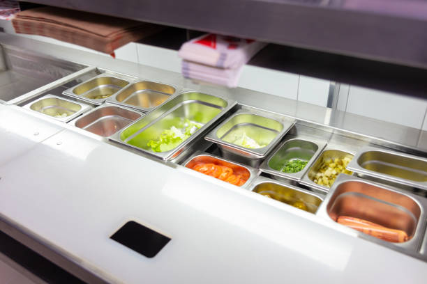 A table with containers of ingredients for cooking fast food in the kitchen of a cafe, pizzeria or restaurant.
