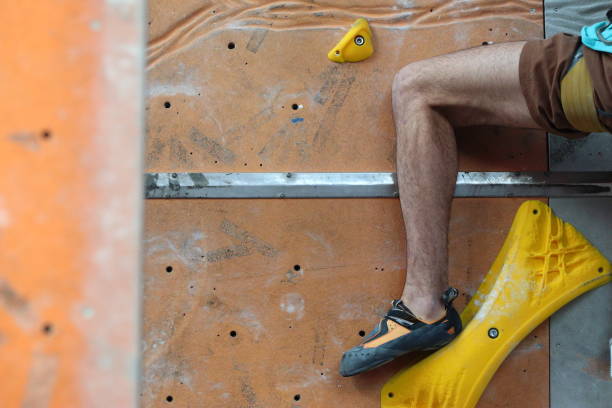 boys during a climbing competition with rope and harness in the gym with colored blocks
