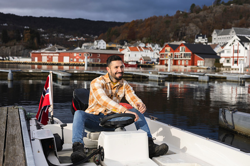 smiling man driving in a small boat in a port Norway