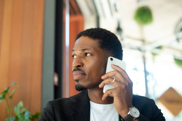 istock Businessman, phone call and thinking in cafe for communication, project ideas and networking with serious face. African person, entrepreneur and thoughtful with smartphone for mobile chat and talking 2022502832