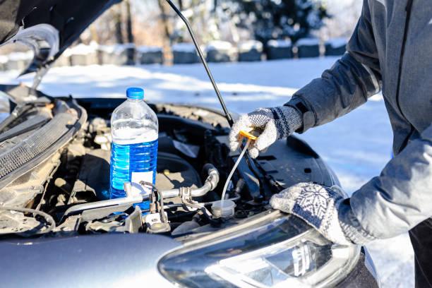 Man checking the level of car windshield liquid on snowy day. Man preparing to pour windshield liquid in tank. Winter outdoor scene. dump radiator stock pictures, royalty-free photos & images
