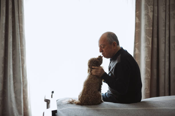 istock Senior Man Sitting On Bed At Home With Pet Toy Poodle 2022562437