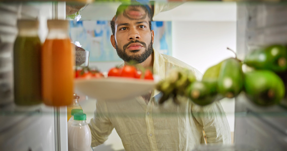 Man looking vegetable food in refrigerator at kitchen.