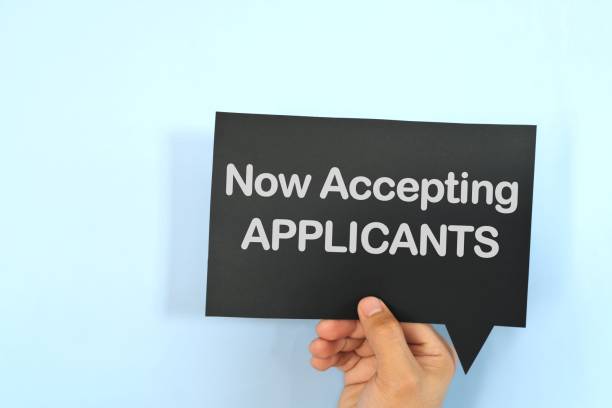istock Human hand holding black speech bubble with written phrase Now Accepting Applicants. Recruitment and job hiring concept. 2022577219