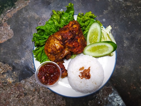 Top view grilled chicken thighs with spicy chili sauce, rice and cucumber