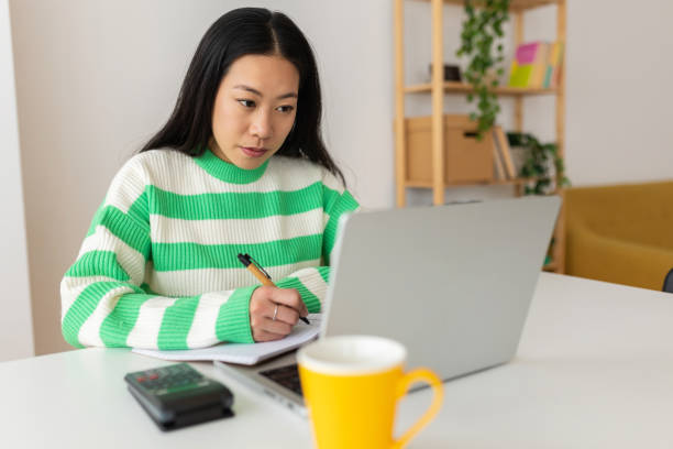 istock Young asian student woman using laptop studying online at home 2022605115