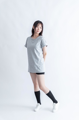 Young Asian woman in gray t-shirt and black shorts posing on white background
