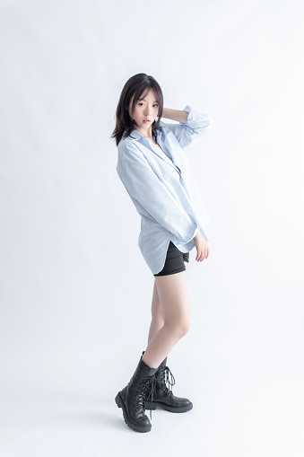 Asian woman in blue shirt and black boots posing
