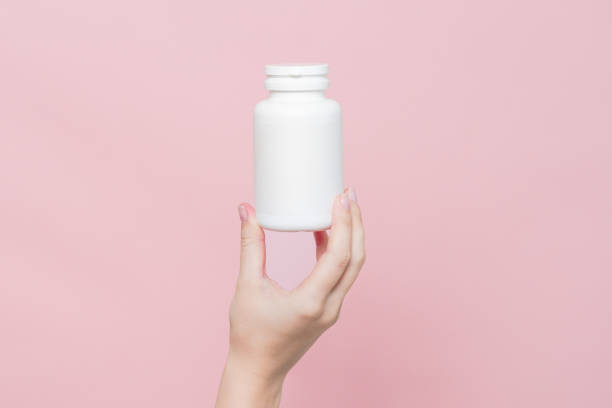 istock Blank white plastic tube in hand on pink background. Cosmetics beauty mockup for product branding 2022624708