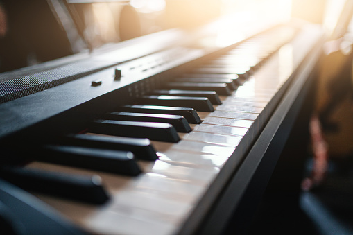Closeup of piano keyboard with sunlight streaming through window, showcasing beauty of this musical instrument