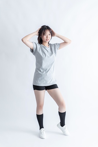 Young Asian woman in a gray t-shirt and black shorts posing with her hands on her head
