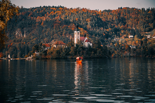 Stunning nature scenery with autumn colour leaves frame and majestic fall season landscape sunrise view of The beauty of Lake Bled in Bled, Slovenia, is truly enchanting, especially during the fall season when the colors come alive, and the aerial view of Blejsko Jezero shows the iconic St. Marys Pilgrimage Church of the Assumption of Maria on the small island.