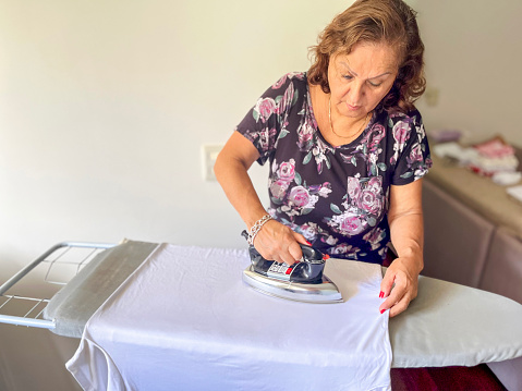 Senior Hispanic woman ironing at home