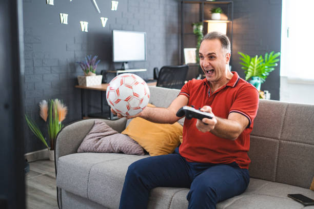 istock Middle age Caucasian man playing soccer video game at home 2022642162