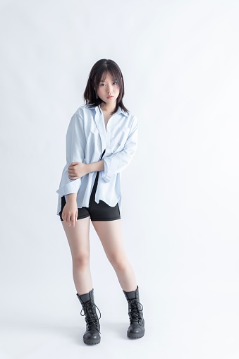 Asian woman in blue shirt and black shorts posing in studio