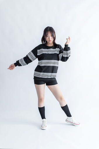 Asian young woman in striped sweatshirt and shorts dancing