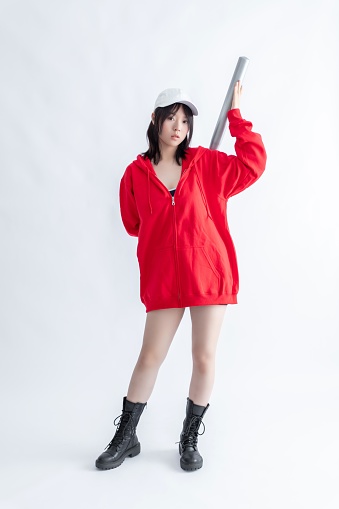 Asian woman in red hoodie and white cap holding a baseball bat