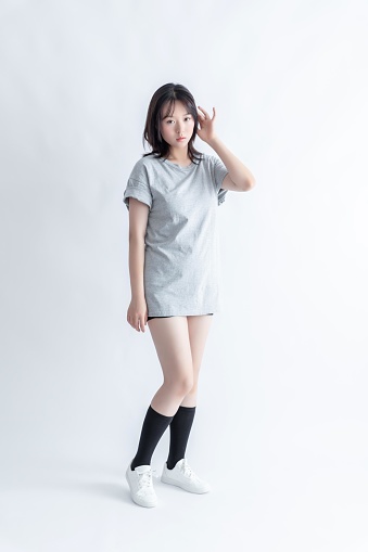 Young Asian woman in gray t-shirt and black shorts posing in studio