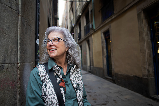 business portrait of a confident successful 60 year old gray-haired woman in glasses dressed in a brown jacket.
