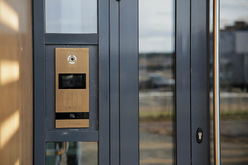 Modern golden entrance doorbell intercom in apartment building, with a video surveillance camera