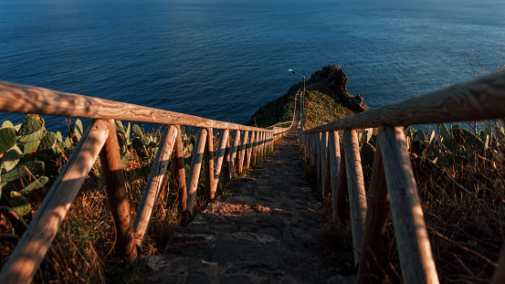 Amazing hill cliff with wooden walkway to the ocean at sunset. Beautiful Madeira island and ocean