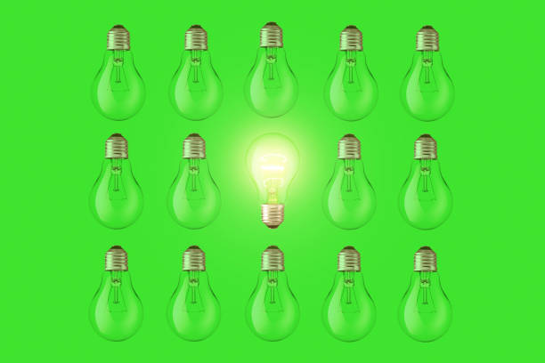 Creative light bulb lies and glows among the extinguished bulbs on a green background, top view. Green energy, a concept. Think different, creative idea. Creative Smart thinking.