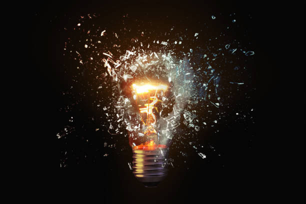 Creative idea light bulb explodes with shards of glass against a dark background. Business, ideas and new thinking, concept. Think Different. Go beyond what is possible.