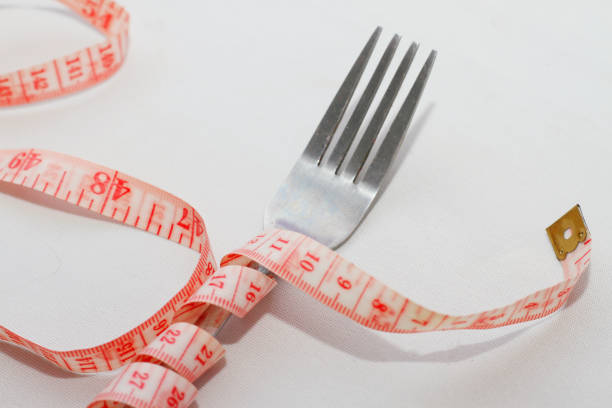 istock Close up of measuring tape and fork on white background,diet concept 2022788448