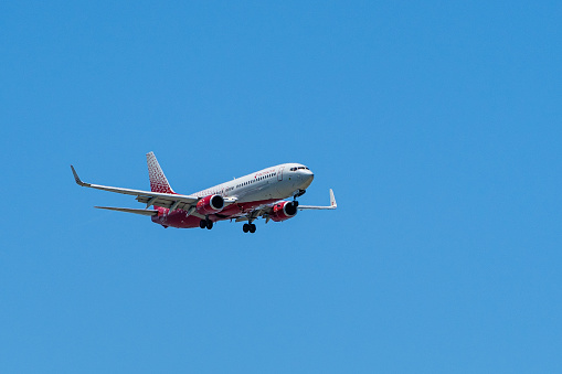 Boeing Boeing 737-800 flies against blue spring sky to Adler airport. Close-up. RUSSIA - RUSSIAN AIRLINES. Aircraft landing gear and flaps extended. Sochi, Russia - May 18, 2021