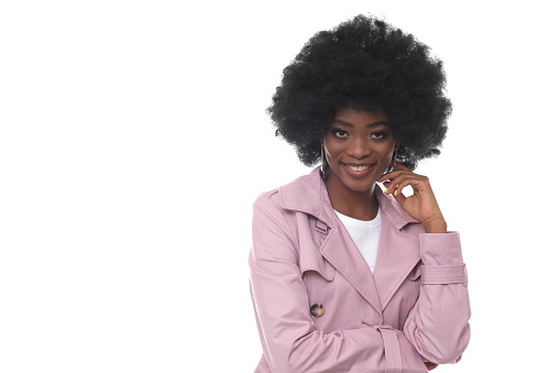 Studio shot of a beautiful black woman with afro hair wearing a pink coat.