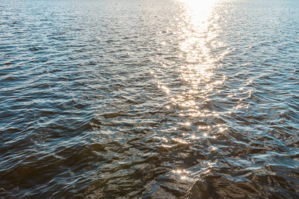 Wonderful natural sun light reflects make sparkles in the sunset evening water.