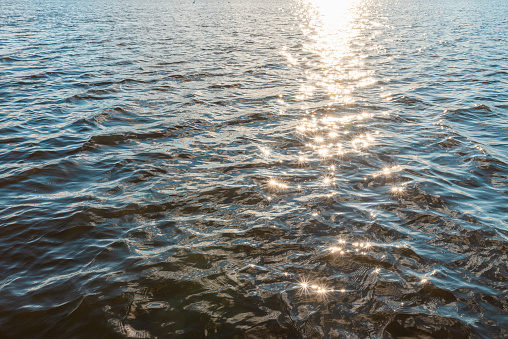 Wonderful natural sun light reflects make sparkles in the sunset evening water.