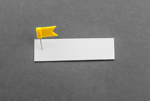 Blank note and yellow thumbtack on a gray background with copy space