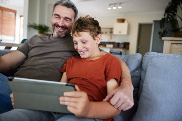 istock Smiling dad and son watching something on a tablet on a sofa 2022811892