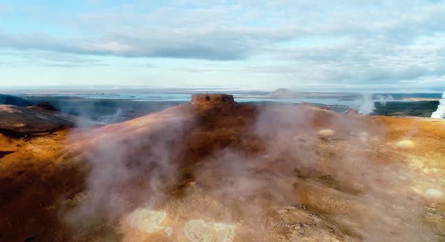 A wonderful shot for hverir area , displaying heights and its beautiful brown color and blue cloudy sky, the steam spreading out the cracks and finally, the nature of hverir appears by its green forests and a small lake beside the geothermal vents