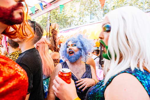 Positive homosexual drinking beverage among excited group of friends having fun and enthusiastic of gay summer party outdoors