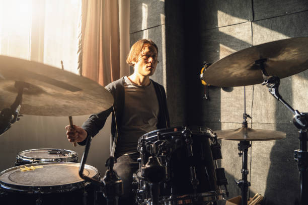 istock Man is energetically play drums in studio, surrounded by musical instruments and equipment. He is focused on his performance, hitting drums rhythmically and creating music 2022839845
