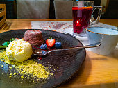 Beautiful and colorful dessert with vanilla ice cream, pistachio, chocolate lava cake, fruits, frozen cheese and fruity tea on decorative plate in small restaurant