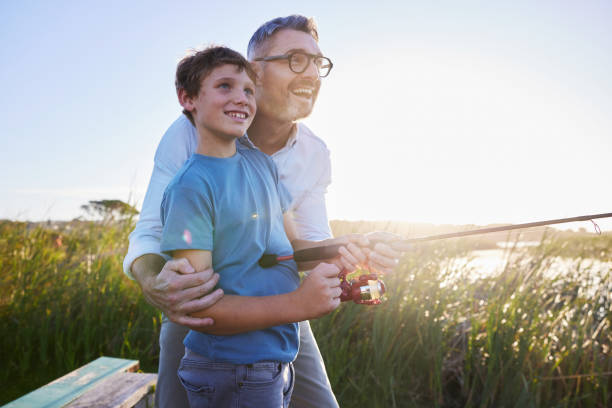 Rear view of father (30s) and son (10 years) going fishing.