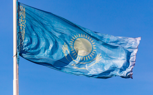 Flag of the Republic of Kazakhstan waving in the wind against the blue sky.