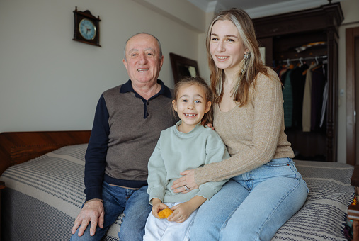 A cropped portrait of a happy multi-generation family sitting together on a bed