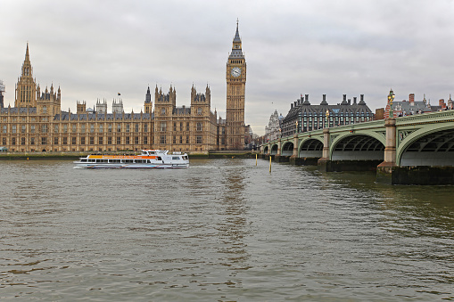 London, United Kingdom - January 26, 2013: Tourist Boat at River Thames in Front of Houses of Parliament and Big Ben Clock Tower British Landmarks in Capital City Winter Day.