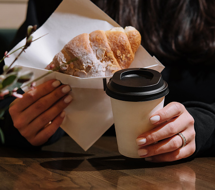 Woman holding a mug of coffee and a croissant