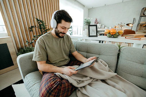 Handsome man uses his tablet at home on the sofa