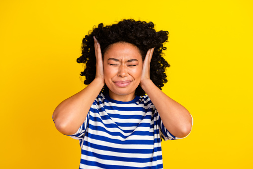 Photo of irritated girl closed eyes wear trendy clothes avoid loud noise sound isolated on yellow color background.
