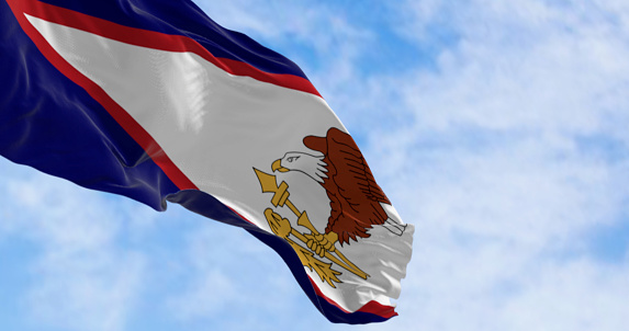 The American Samoa flag waving in the wind on a clear day. Unincorporated territory of the United States located in the South Pacific Ocean. 3d illustration render. Selective focus
