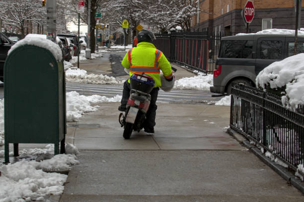 zusteller fährt mit einem elektromotorrad auf dem bürgersteig in brooklyn. - motorcycle snow winter new york city stock-fotos und bilder